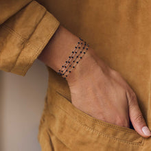 Poignet d’une femme portant différents bracelets de la nouvelle collection en or noir Gigi Clozeau.
