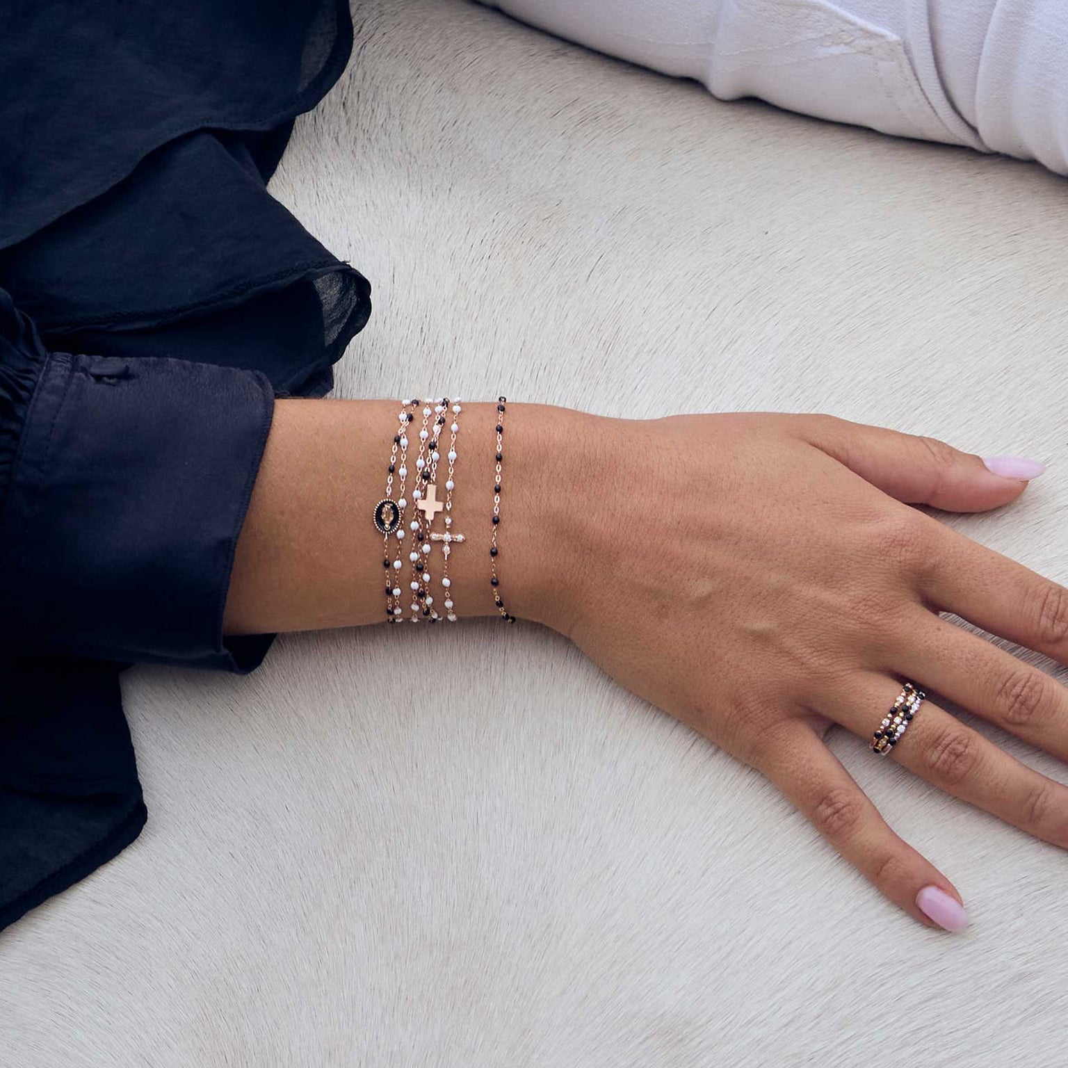 Photo du poignet d’une femme posé sur un cheval, portant plusieurs bracelets Gigi Clozeau noirs et blancs.