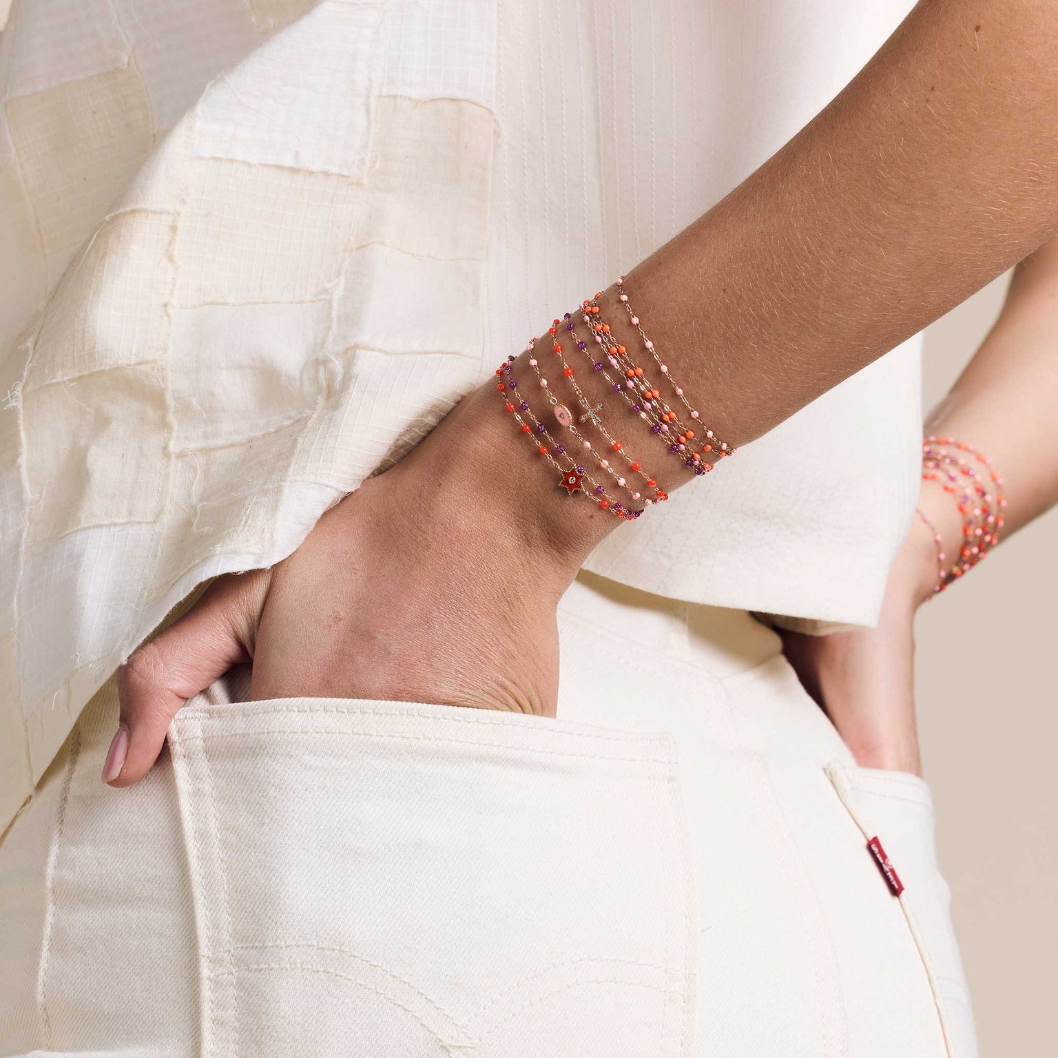 Photo d'une femme avec les mains dans les poches arrière, portant des bracelets Gigi Clozeau autour des poignets.