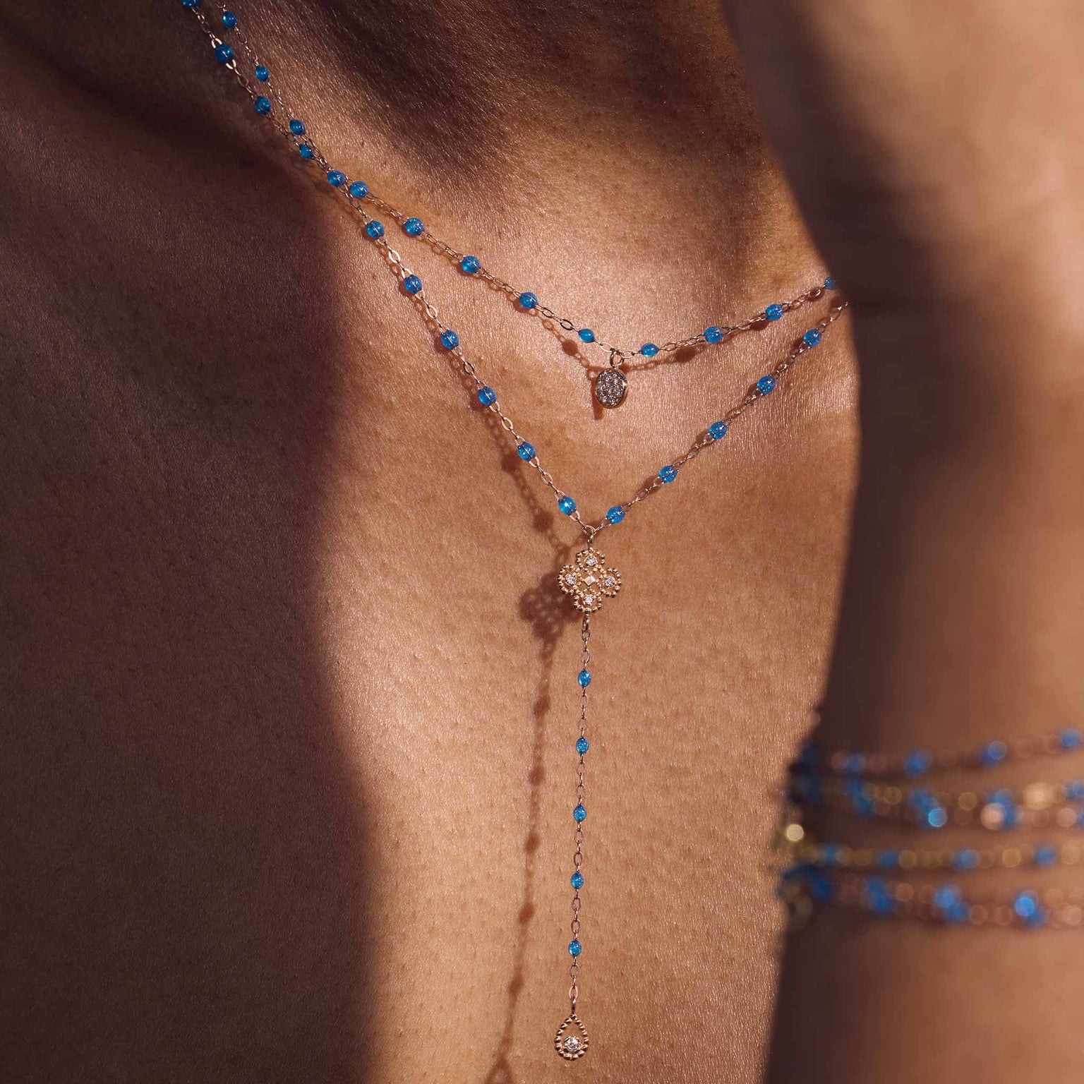 Photo du décolleté d’une femme portant deux colliers Gigi Clozeau de la nouvelle couleur azur.