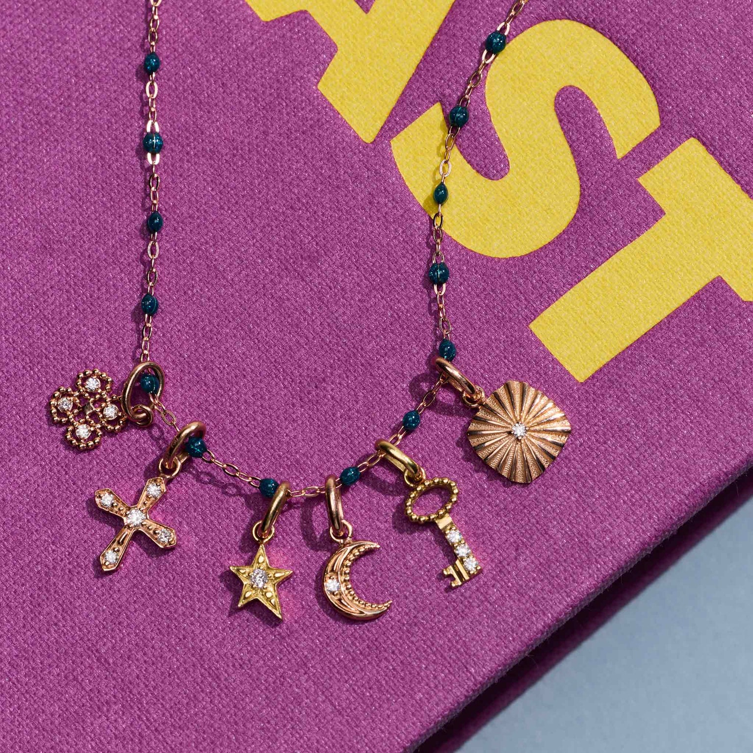 Photo de différents pendentifs Gigi Clozeau sur un collier Gigi Clozeau posé sur un livre.