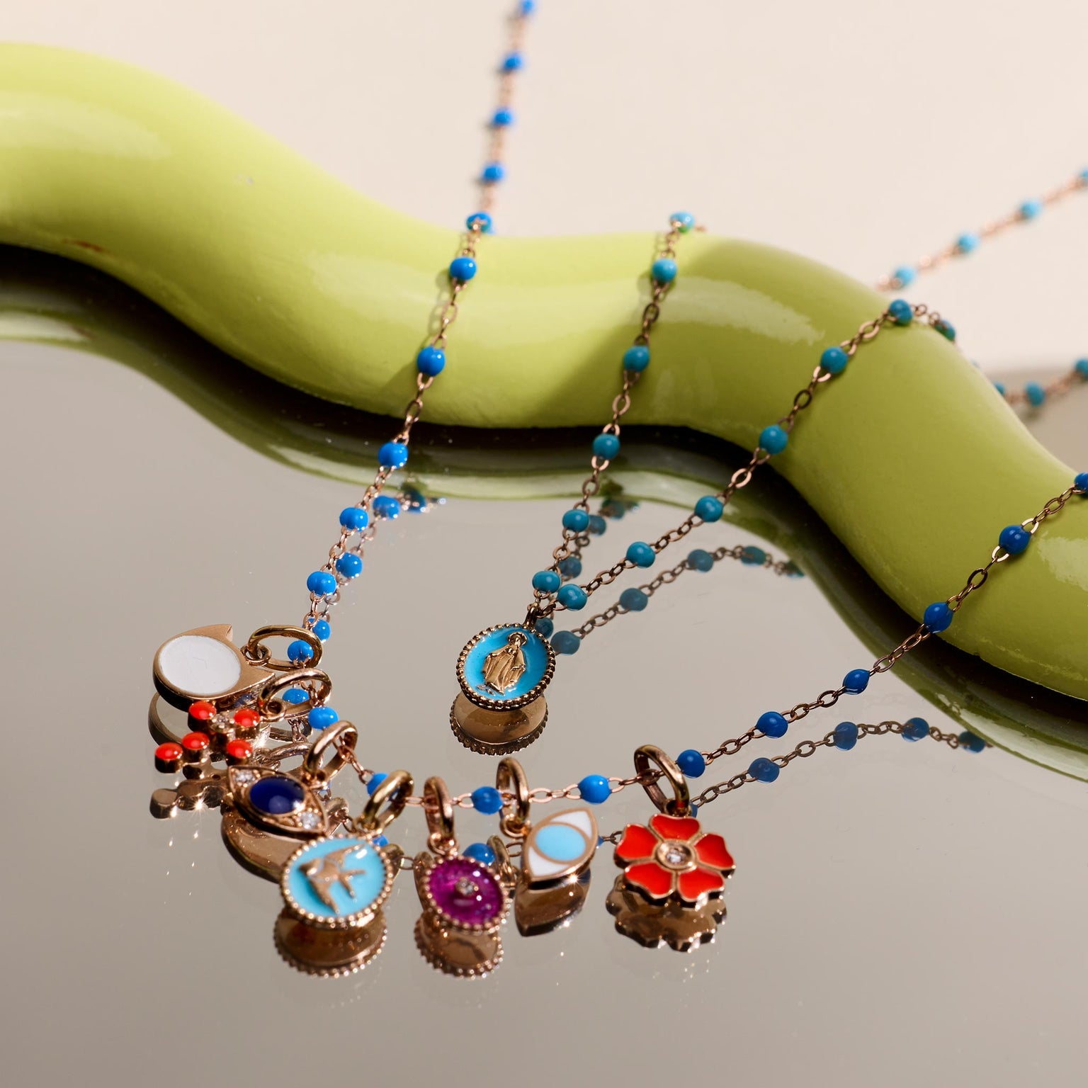 Photo de différents pendentifs Gigi Clozeau posés sur un miroir.